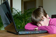 young boy thinking on laptop at home