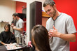 Smiling male hairdresser cutting hair