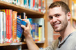 Smiling male student picking a book