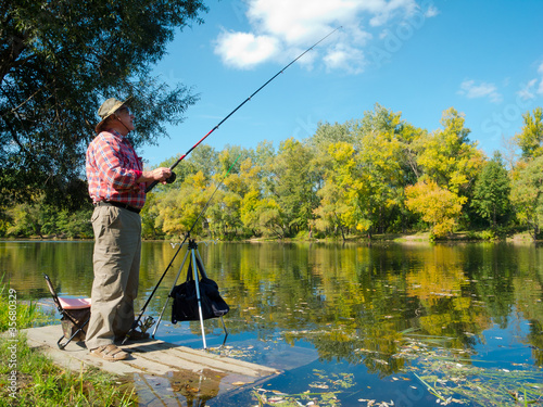 Photo: Senior fisherman catches a fish Senior fisherman catches a fish