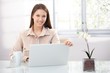 Photo: Pretty female using laptop at home smiling Pretty female using laptop at home smiling