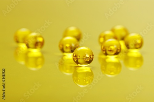 Photo: Macro of E vitamine capsules on yellow Macro of E vitamine capsules on yellow