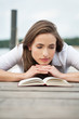 junge Frau, die ein Buch auf einem Steg liest