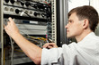 The engineer stand in datacenter near telecomunication equipment