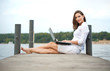 attraktive junge Frau, die am Laptop am Wasser arbeitet