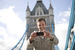 A man taking a photograph of himself in front of Tower Bridge