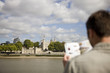 A man in front of the Tower of London, looking at a guidebook