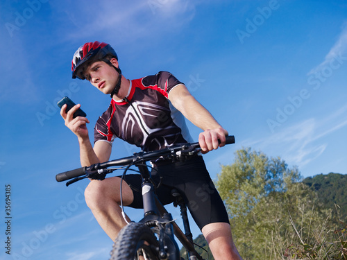 Photo: young man with telephone riding mountain bike young man with telephone riding mountain bike
