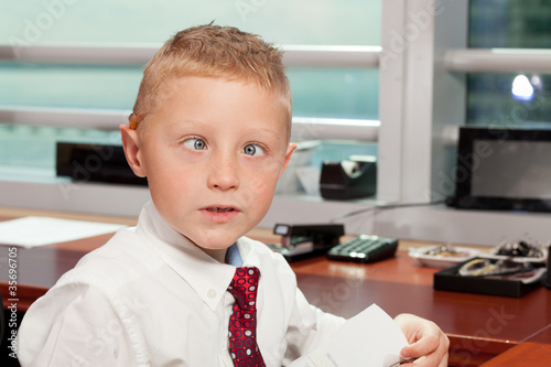 Photo: Cute boy with goofy face in business attire in an office Cute boy with goofy face in business attire in an office
