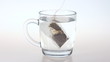 A tea bag in glass cup boiling water.