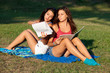 Pretty young female college students studying on a campus field