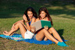 Pretty young female college students studying on a campus field