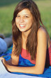 Pretty young female college student studying on a campus field