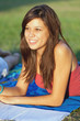 Pretty young female college student studying on a campus field