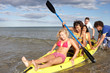Teenagers in sea with canoe