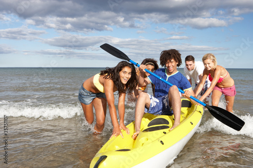 Photo: Teenagers in sea with canoe Teenagers in sea with canoe