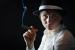 Photo: Woman in black hat with cigar in isolated Woman in black hat with cigar in isolated
