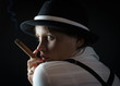 Photo: Woman in black hat with cigar in black isolated Woman in black hat with cigar in black isolated