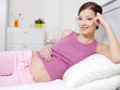 pregnant woman lying on bed and touching her stomach