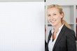 lächelnde blonde geschäftsfrau steht am flipchart