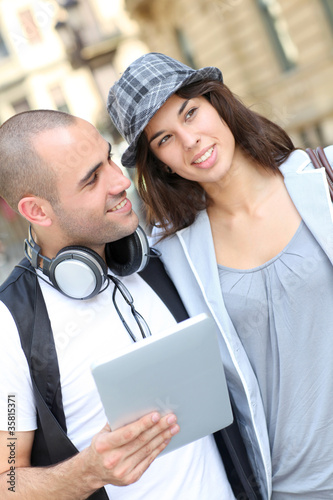 Foto: Young couple using electronic tablet in town Young couple using electronic tablet in town