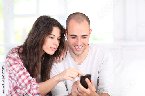 Photo: Young couple doing online shopping with smartphone Young couple doing online shopping with smartphone