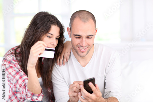 Photo: Young couple doing online shopping with smartphone Young couple doing online shopping with smartphone