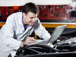 Motor mechanic is tuning the engine of a car with laptop