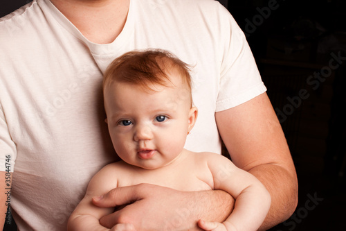 Photo: Father in white shirt holding infant child Father in white shirt holding infant child