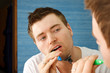Photo: Man multitasking by brushing teeth and shaving Man multitasking by brushing teeth and shaving