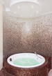 White round jacuzzi in modern bathroom with brown mosaic and cou