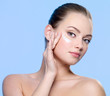 Woman applying cream on face near the eyes
