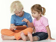 Foto: Cute girlfriends sitting on the floor and playing with touchpad Cute girlfriends sitting on the floor and playing with touchpad