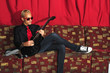 Cool guitarist sitting on red couch