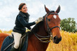 Pretty girl riding horse front of reed