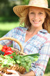 Woman with a straw hat holding basket of vegetables.