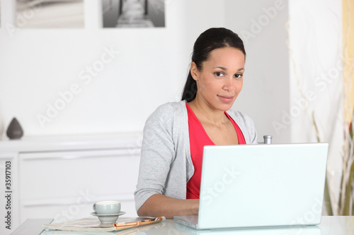 Photo: Woman sat with cup of coffee by laptop Woman sat with cup of coffee by laptop