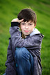 Foto: Boy in jeans sits on a grass Boy in jeans sits on a grass