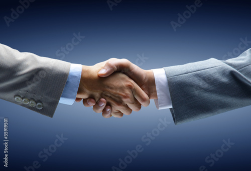 Photo: Handshake - Hand holding on black background Handshake - Hand holding on black background