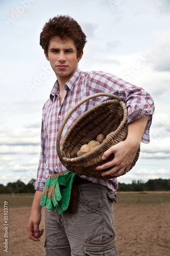 Photo: young handsome farmer on the field during harvest season young handsome farmer on the field during harvest season