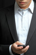 business man in black suit working on pda or smartphone