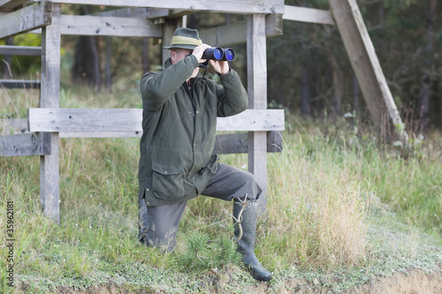 Photo: Jäger mit Fernglas vor Hochsitz Jäger mit Fernglas vor Hochsitz