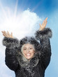 Pretty young woman with pelt cap is playing with snow