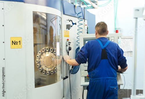 Foto: worker operating CNC machine center worker operating CNC machine center