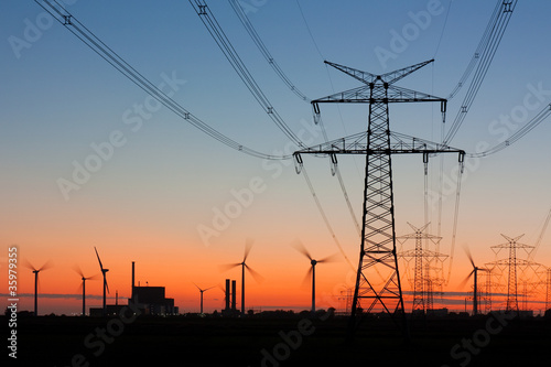 Foto: Strommast bei Sonnenuntergang mit Windrädern und Kernkraftwerk Strommast bei Sonnenuntergang mit Windrädern und Kernkraftwerk