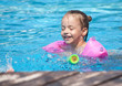 Joyful little girl swimming in the pool.