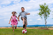 Geschwister spielen Fußball im Garten