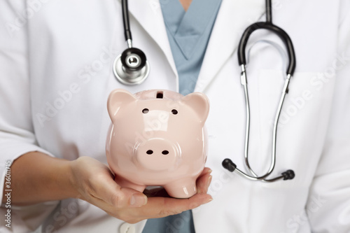 Photo: Doctor with Stethoscope Holding Piggy Bank Abstract Doctor with Stethoscope Holding Piggy Bank Abstract