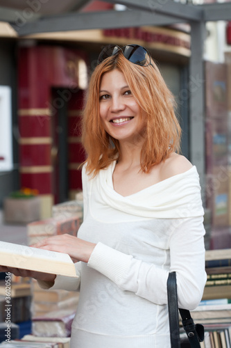 Photo: girl selects the book from street shop. girl selects the book from street shop.