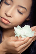 Beautiful young woman holding a white flower near her face Beautiful young woman holding a white flower near her face